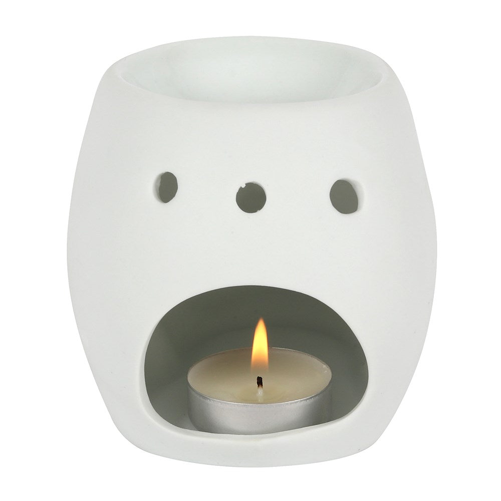 White skull ceramic oil burner with a lit candle inside on a white background