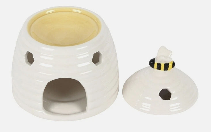 A white ceramic beehive-shaped warmer with a matching lid featuring a small bumblebee accent on top, shown on a plain light gray background.