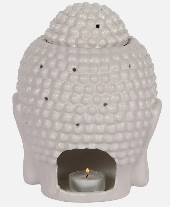 A grey ceramic Buddha head wax burner with a lit tealight candle inside. 